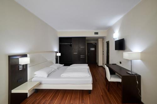 a bedroom with a white bed and a desk at Kona Hotel Verona in Negrar