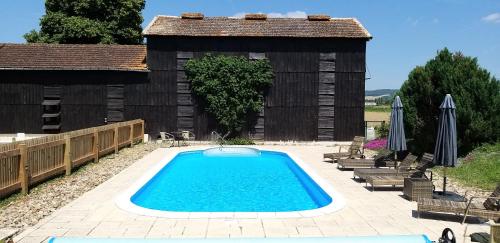 - une piscine en face d'un bâtiment en bois dans l'établissement Hortensia & Rose Gites, à Montpezat