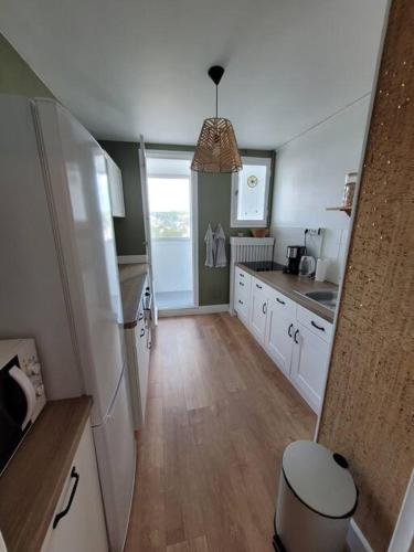 a kitchen with white cabinets and a large window at Appart Familial, prox Gare & Centre-ville, garage in Besançon
