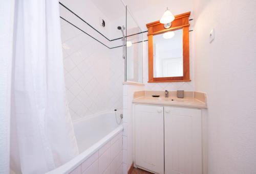 une salle de bain avec un lavabo, une baignoire et un miroir dans l'établissement Smartstay Ocean - Lacanau, à Lacanau