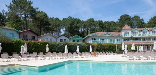 un complexe avec une piscine, des chaises et des parasols dans l'établissement Smartstay Ocean - Lacanau, à Lacanau