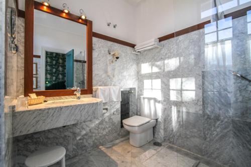W łazience znajduje się umywalka, toaleta i lustro. w obiekcie Silken Gran Hotel del Sella w mieście Ribadesella
