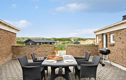a patio with a table and chairs and a brick wall at Four-Bedroom Holiday Home In Hvide Sande in Bjerregård