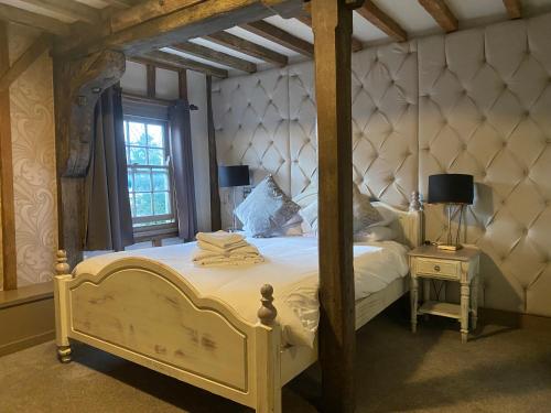 1 dormitorio con 1 cama blanca con marco de madera en The Riverside Inn en Chelmsford