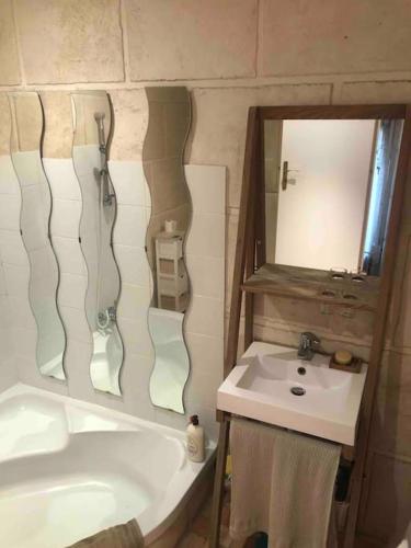 une salle de bain avec un lavabo, une baignoire et un miroir dans l'établissement Charmant appartement atypique Boulogne Billancourt, à Boulogne-Billancourt