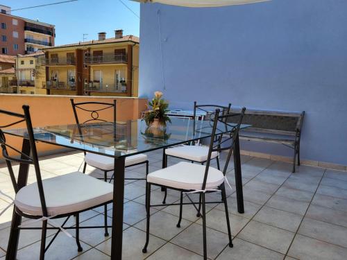 un tavolo in vetro e sedie su un balcone con panca di Da Panco e Vera a Porto Recanati