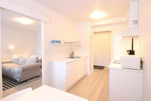 a white kitchen with a sink and a living room at Forenom Serviced Apartments Hämeenlinna Katuma 1 in Hämeenlinna