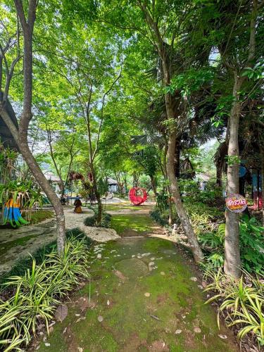 a park with trees and a path in the grass at Clay House Chiang Mai By Alphatel in Chiang Mai