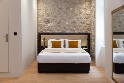 a bedroom with a bed with white sheets and gold pillows at Epitome Suites in Athens