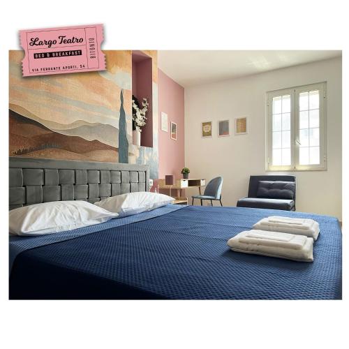 a bedroom with a blue bed with two towels on it at Largo Teatro Bed & Breakfast in Bitonto