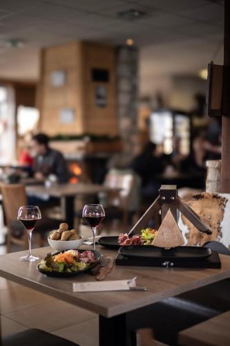 une table avec deux assiettes de nourriture et des verres de vin dans l'établissement Le Saint Jo - La Féclaz, à Les Déserts