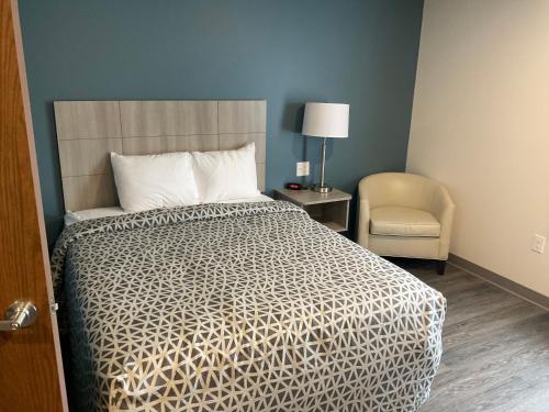 sypialnia z łóżkiem, krzesłem i lampką w obiekcie WoodSpring Suites Winston-Salem near Hanes Mall w mieście Winston-Salem