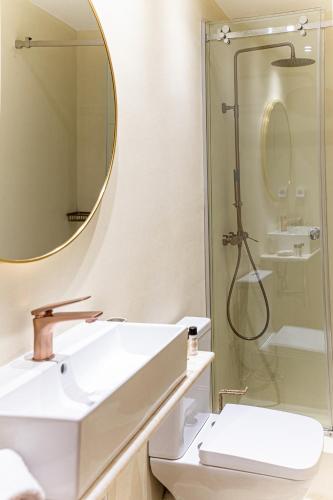 a white bathroom with a sink and a shower at Epitome Suites in Athens