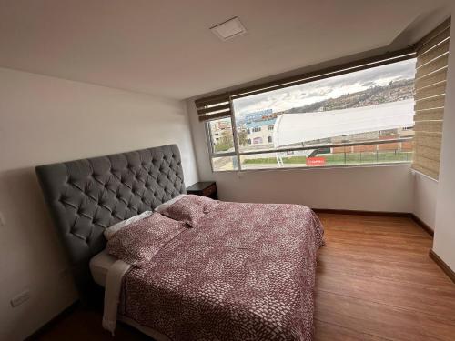 um quarto com uma cama e uma grande janela em Instant Hotel - Villa Palermo Luxury Apartments em Ambato