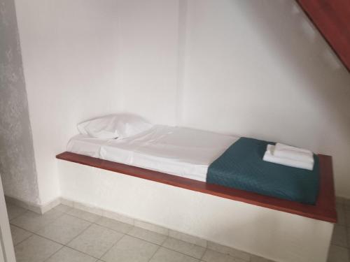 een klein bed in een witte kamer met een plank bij ANATOLI LYGARIA APTs on the beach in Lygaria