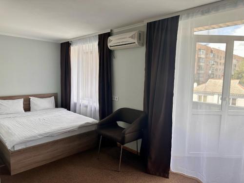 a bedroom with a bed and a chair and a window at Yavir in Poltava