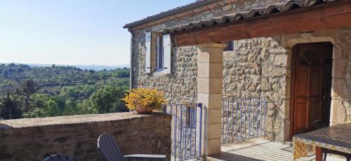 Cette maison en pierre dispose d'un balcon avec une table et des chaises. dans l'établissement Domaine L'Amourie Sud Ardèche, à Saint-Étienne-de-Fontbellon