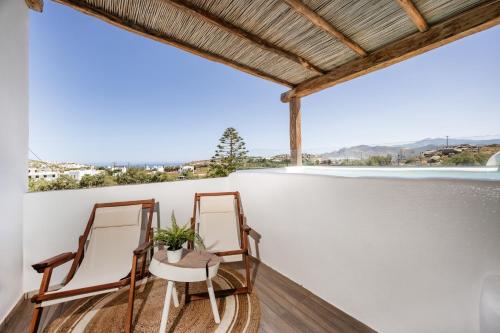 two chairs on a balcony with a view at Thea Suites Naxos in Agios Prokopios