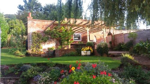 a garden with a brick house with a pergola at The Garden Studio Woodcombe in Minehead