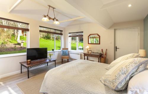 a bedroom with a bed and a flat screen tv at The Garden Studio Woodcombe in Minehead