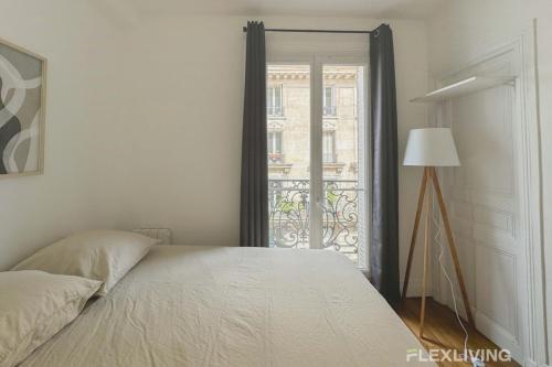 - une chambre avec un lit et une porte donnant sur un balcon dans l'établissement Flexliving - Room - Lamarck, à Paris