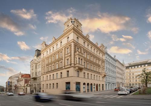 um grande edifício branco numa rua da cidade com carros em NOBILIS RESIDENCE em Praga