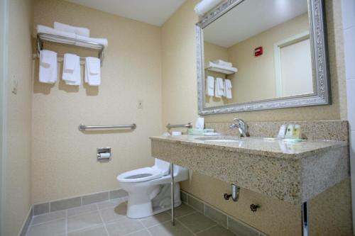 a bathroom with a sink and a toilet and a mirror at Corona Hotel New York - LaGuardia Airport in Queens