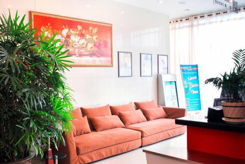 an orange couch in a room with plants at Jinjiang Inn Wuxi West Jiefang Road Chong'an Temple in Wuxi