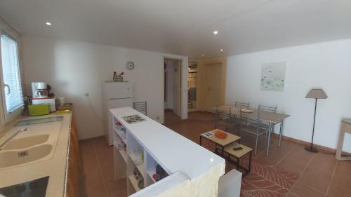 Il comprend une cuisine équipée d'un réfrigérateur et d'une table avec des chaises. dans l'établissement Logement indépendant, piscine, pool-house et terrasse privés, à Castelnau-de-Guers