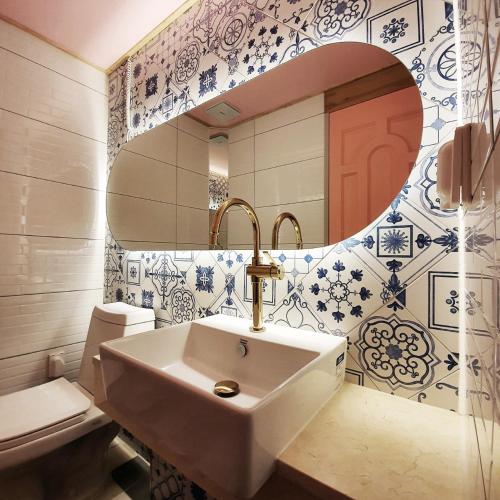 a bathroom with a sink and a toilet and a mirror at Ariene Guesthouse in Gwangju