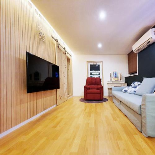 a living room with a couch and a television on a wall at Ariene Guesthouse in Gwangju