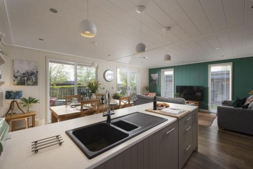 a kitchen and living room with a sink and a table at Cedar Lodge, Strawberryfield Park in Cheddar