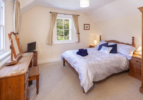 a bedroom with a bed and a desk and a television at Lorna Doone Cottage, Lynmouth in Lynmouth