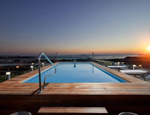 a large swimming pool with a sunset in the background at CW Athens Riviera Suite in Athens