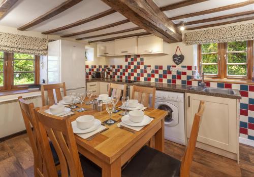 a kitchen with a wooden table with chairs and a sink at Old Malthouse in Monksilver