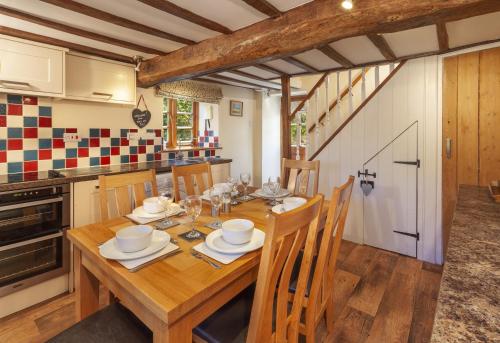 a dining room with a wooden table and a kitchen at Old Malthouse in Monksilver
