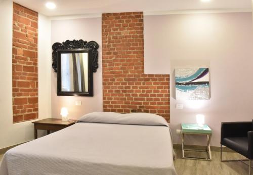 a bedroom with a bed and a brick wall at Ventitrémarzo Guest House in Novara