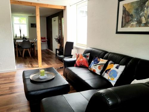 a living room with a black leather couch and a table at Ferienwohnung Südheide in Beedenbostel