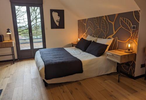 ein Schlafzimmer mit einem großen Bett mit einem Baumbild an der Wand in der Unterkunft Gite les Caravottes 4 Etoiles avec Jacuzzi - JURA in Courlaoux