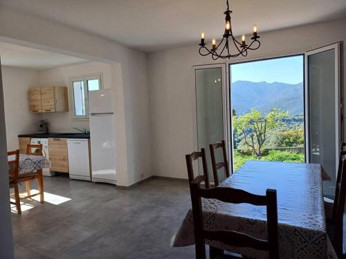 une salle à manger avec une table et une cuisine avec vue dans l'établissement Maison à 15 minutes de Propriano, à Santa-Maria-Figaniella