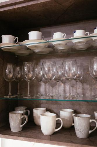 a shelf with wine glasses and cups on it at LILY'S VILLA LEMONIA in Platanes