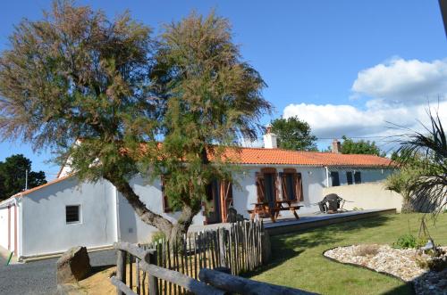 une maison blanche avec une clôture et un arbre dans l'établissement Maison Tamaris proche de l'Océan, à LʼAiguillon-sur-Vie