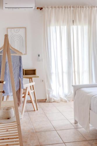 a bedroom with white curtains and a bed and a ladder at The Yard Residence in Gavalochori
