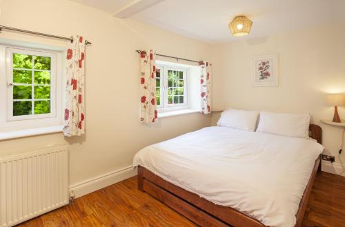 a bedroom with a bed and two windows at Jasmine Cottage Porlock in Porlock