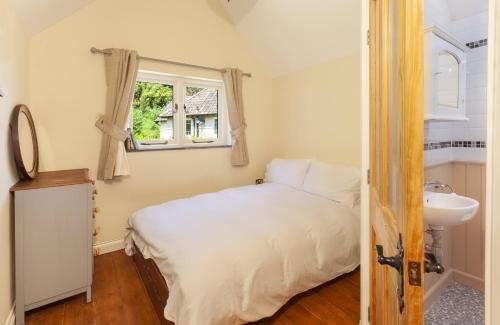 a bedroom with a bed and a sink and a window at Jasmine Cottage Porlock in Porlock