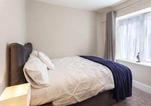 a bedroom with a bed with white sheets and a window at The Lofthouse, Minehead in Minehead