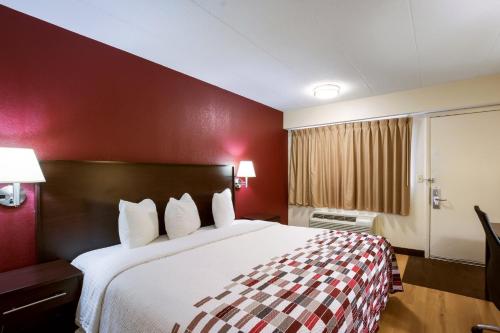a hotel room with a large bed with red walls at Red Roof Inn Kalamazoo East – Expo Center in Kalamazoo