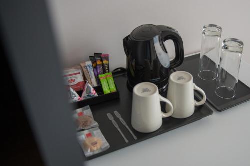 a shelf with two mugs and a coffee pot on it at Garden Court Kitwe in Kitwe