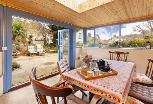 a dining room with a table and chairs and windows at Grist Mill, Dunster in Dunster