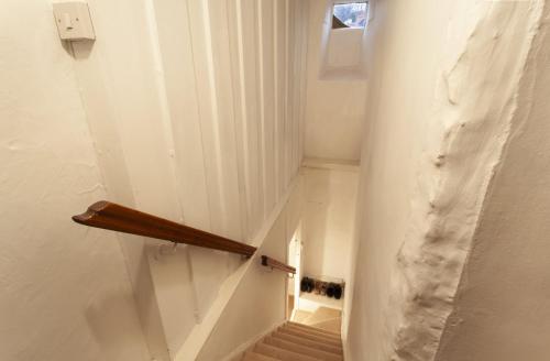 a stairway with a wooden rail in a white wall at Grist Mill, Dunster in Dunster